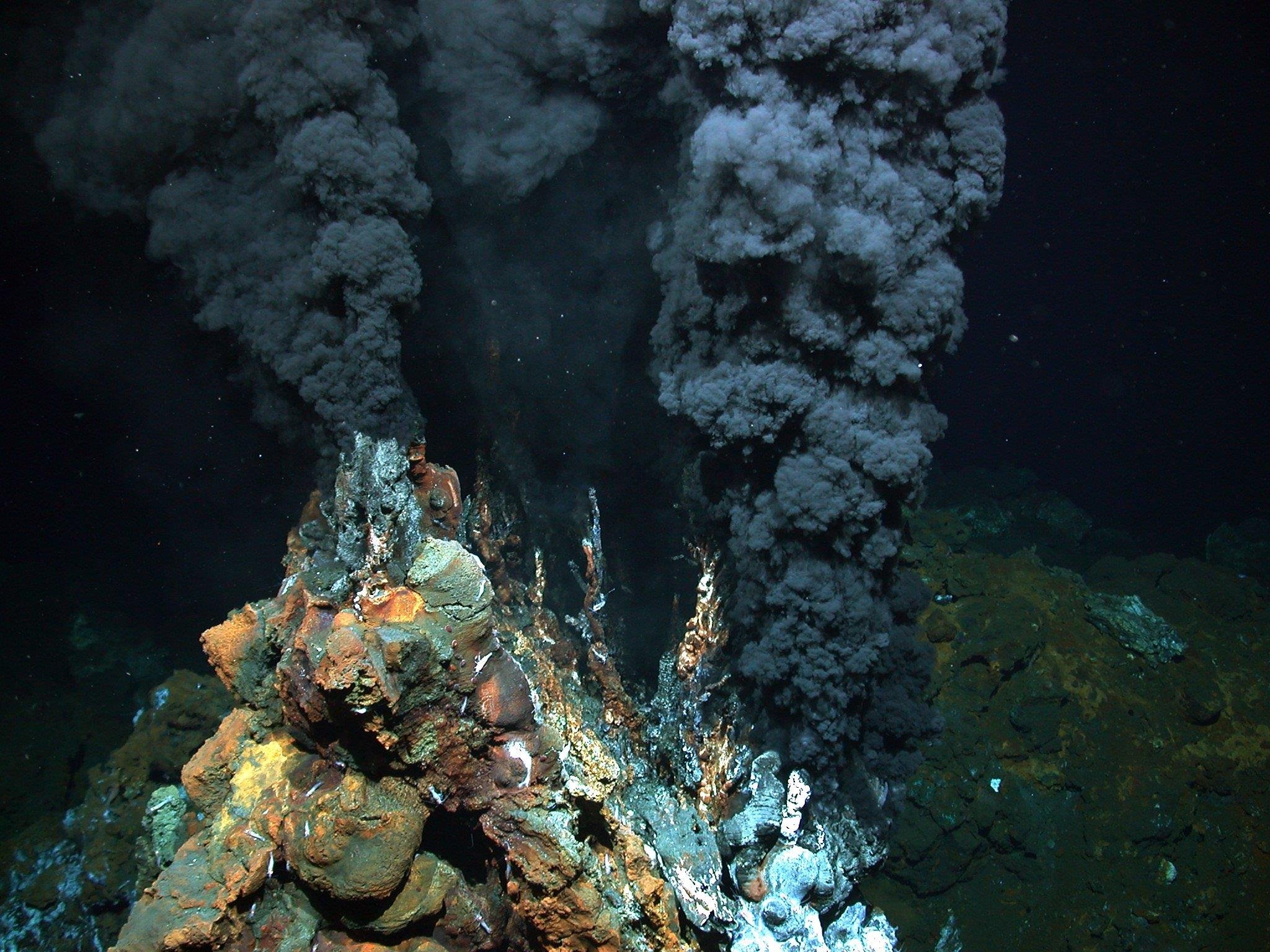 Photograph of a black smoker hydrothermal vent chimney releasing dark mineral-laden plumes on the ocean floor, unlabelled